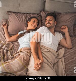 Young couple is resting in bed after work. Stock Photo