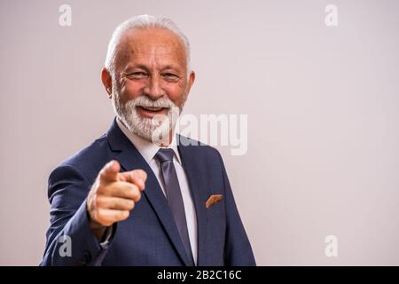 Portrait of happy senior businessman who is pointing at you. Stock Photo