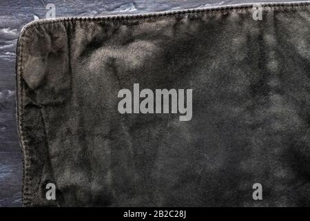 black structural background - old shabby stylish suede, reverse side, old fabric, textile. piece of leather bag, back side on dark, Visible edges with Stock Photo