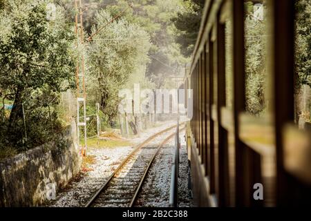 Retro wooden train traveling along railroad in mountains. Beautiful sunny summer landscape. Majorca, Spain. Stock Photo