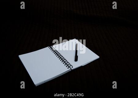 open notebook to point with a pen on a dark background Stock Photo