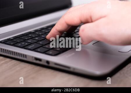 Man's hand typing on a silver laptop with black keys. Online work in progress , programmer work freelance Stock Photo
