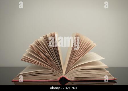 Beautiful open book on a gray and glass table background. Stock Photo