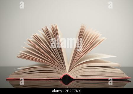Beautiful open book on a gray and glass table background. Stock Photo