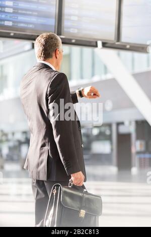 Businessman looking on his watch while waiting for boarding in airport Stock Photo