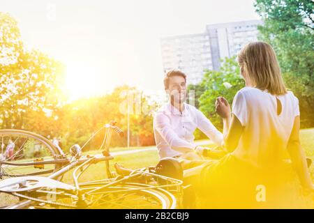 Young attractive business couple talking while sitting on the grass in park Stock Photo