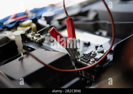 Close-up of battery car jumper on the red positive pole while battery service before change new one for feeding electrical to the car before replace w Stock Photo