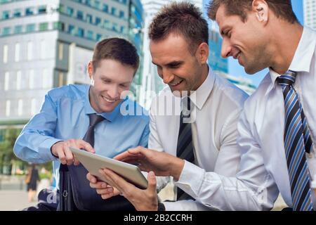 Portrait of handsome businessman showing business plan to the other businessman over digital tablet while sitting