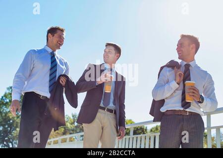 Businessmen drinking coffee while walking and talking during break Stock Photo