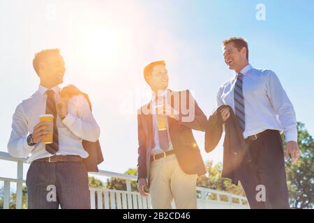 Businessmen drinking coffee while walking and talking during break Stock Photo