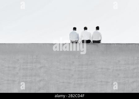 Black and white photo of mature thoughtful businessmen sitting on office rooftop Stock Photo