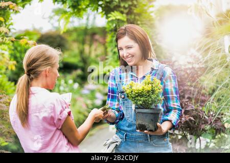 Portrait of woman buying plant on a pot from gardener Stock Photo