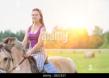 Portrait of young attractive woman riding horse in ranch Stock Photo