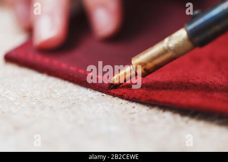 A leather craftsman works with leather. Sews leather goods. Making things handmade. Women's hands with a needle, thread, scissors and a blowtorch. Clo Stock Photo