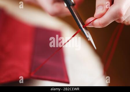 A leather craftsman works with leather. Sews leather goods. Making things handmade. Women's hands with a needle, thread, scissors and a blowtorch. Clo Stock Photo