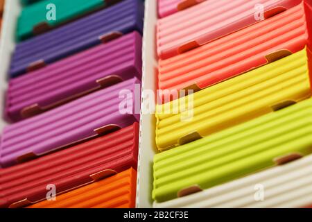 Plasticine in a box of multi-colored pieces in full screen, material for modeling. Close up. Stock Photo