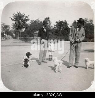 Antique 1898 photograph, young boy in sailor outfit talking to man with dogs in Central Park, New York City, New York. SOURCE: ORIGINAL PHOTOGRAPH Stock Photo