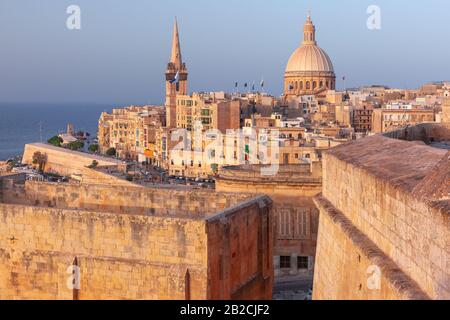 View of Old town roofs, fortress, Our Lady of Mount Carmel church and St. Paul's Anglican Pro-Cathedral at sunset , Valletta, Capital city of Malta