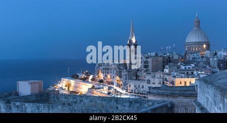 View of Old town roofs, fortress, Our Lady of Mount Carmel church and St. Paul's Anglican Pro-Cathedral at night, Valletta, Capital city of Malta
