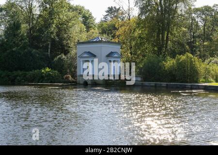 A modern nymphaeum on the edge of the Oval Lake beside woodland in autumn sunshine at the popular parkland estate at Oakfield Park, Raphoe, Co Donegal. Stock Photo