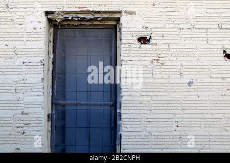 an old alley whitewashed brick wall with locked blue gate door Stock Photo