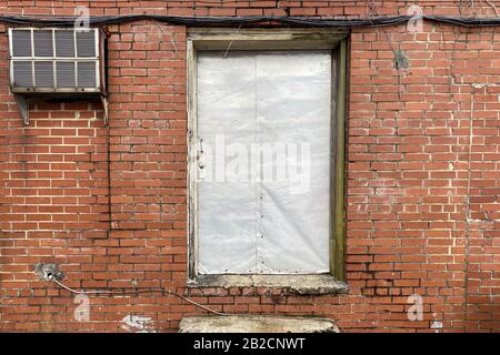 an old locked sheet metal back door on a retro red brick warehouse building Stock Photo