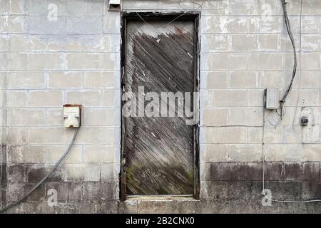 an old wood door on a  concrete abandoned alley warehouse building Stock Photo