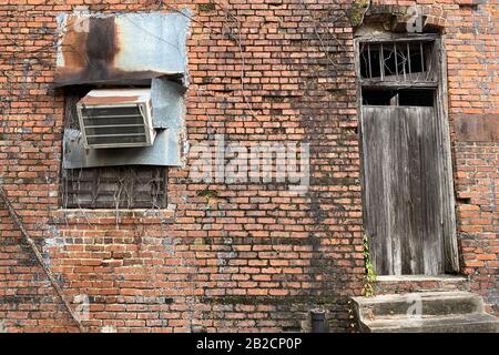 an abandoned vintage office back door boarded up and locked at a retro red brick building Stock Photo