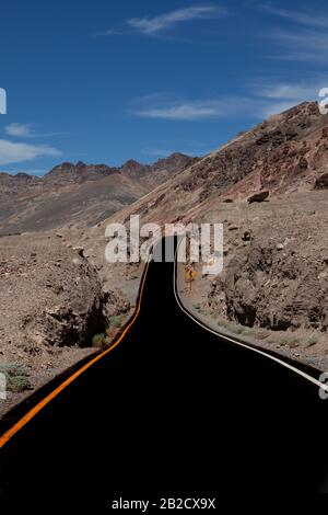 Suggestive winding road leading somewhere in the desert of Death Valley National Park, a ribbon among the arid rocks Stock Photo