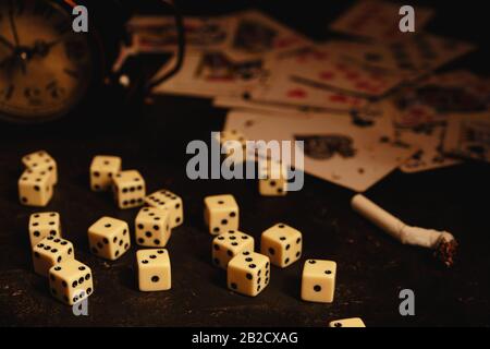 Dice,cigarettes, cards, and an abandoned alarm clock on a table in an underground casino Stock Photo