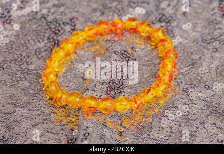 Beautiful vivid golden amber bracelet with even round beads lying on shiny silver background Stock Photo