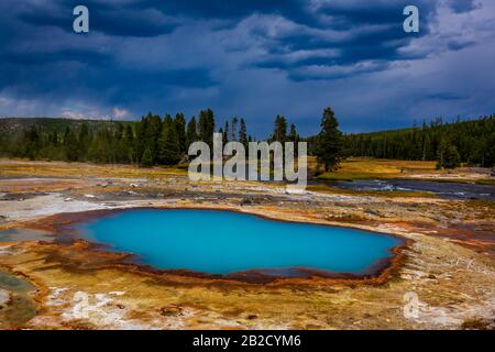 Black Opal Pool is an opalescent blue colored hot pool in Biscuit Basin, Yellowstone National Park Stock Photo