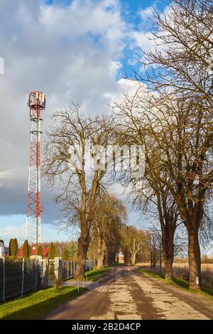 Countryside road with telecommunication tower with antennas aside. Stock Photo