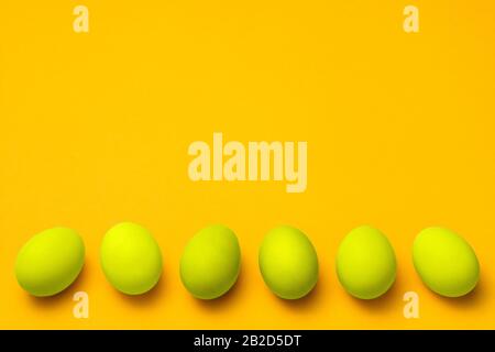 yellow colored eggs in a row on yellow background with copyspace Stock Photo