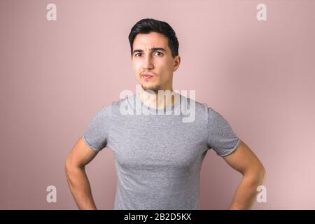 handsome man in grey t-shirt thinking looking directly in the camera Stock Photo