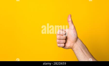 closeup hand with big thumb down over a wide yellow banner background with copyspace. dislike sign Stock Photo