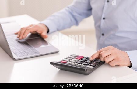 Mature man using laptop and calculator at office Stock Photo