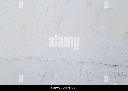 Close-up of a cracked concrete wall painted in white. High resolution full frame textured background. Stock Photo