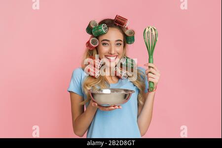 Smiling beautiful housewife holding bowl and a whisk Stock Photo