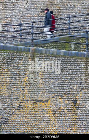 A man and a woman couple walking down a steep slope or some steps at Cromer seafront on the north norfolk coast, Stock Photo