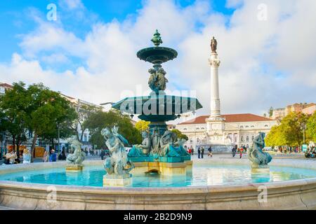 LISBON, PORTUGAL - JANUARY 28, 2020: People at Rossio fountain with statues and Column of king Pedro IV in the background Stock Photo