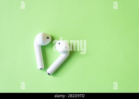 Wireless white headphones on a green background. Colorful spring concept Stock Photo