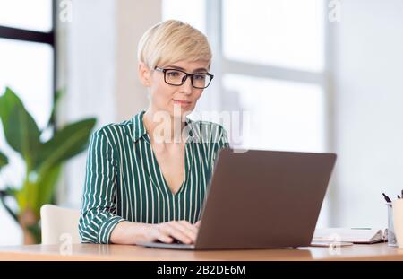 Office Manager Lady Working On Laptop Sitting At Workplace Indoor Stock Photo