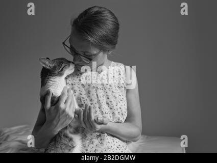 Woman with cat on bed petting at home Stock Photo
