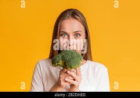 Young Woman Eating Broccoli, Biting Healthy Vegetable With Wide-Opened Eyes