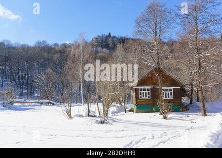 Rustic wooden house in a snowy winter forest on the mountain in cold Sunny day. Russia, Lago-Naki, Adygeya Republic Stock Photo