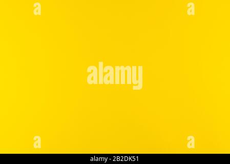 Yellow background of real colored paper, illuminated by a soft light on the sides. Stock Photo
