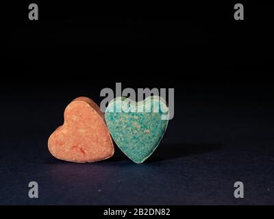 Two heart-shaped candies on the black background. Stock Photo