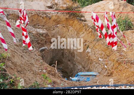deep excavation with caution posts side of a road, part of construction work Stock Photo