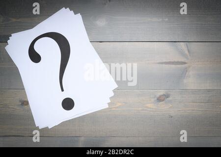 Stack of question marks printed on white paper on a gray board background Stock Photo